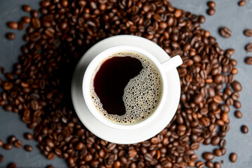 Warm cup of coffee with coffee beans over black background. Coffee time, copy space web design banner.