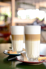 Glass of hot Latte macchiato coffee close up. Two glasses of coffee latte. Blurred background.