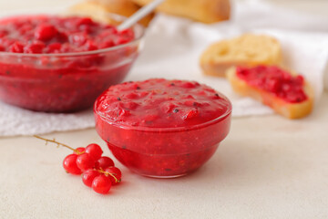 Bowl with red currant jam on light background