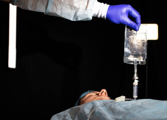 The doctor puts a dropper on the patient's girl to thin the blood and raise hemoglobin, background....