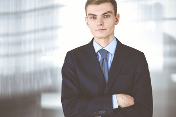 Young businessman wearing suit and tie, while standing in the office. Business success concept nowadays