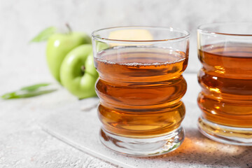 Glasses of apple juice on light background, closeup