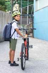 Boy arrives at school on his bike with his helmet and backpack for the start of school. Back to school concept. High quality photo