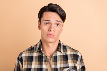 Photo of millennial unsure guy wear checkered shirt isolated on beige color background