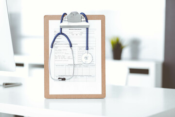 Stethoscope and clipboard with medication history records are on the table at the doctor's working place. Medicine and health care concept