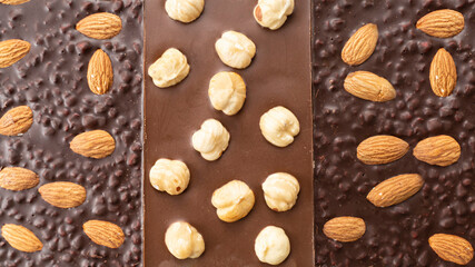 Handmade milk and dark chocolate bars with a variety nuts. Top view Assortment of fine chocolates with almonds, hazelnuts