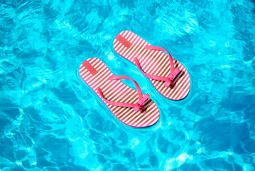 Pair of red and white striped flip flops in a pool