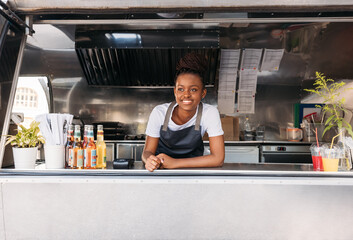 Portrait of young saleswoman waiting for clients. Food truck owner leaning on a counter looking away. - Powered by Adobe