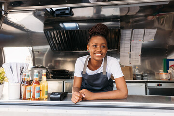 Portrait of young small business owner standing in her food truck waiting for clients