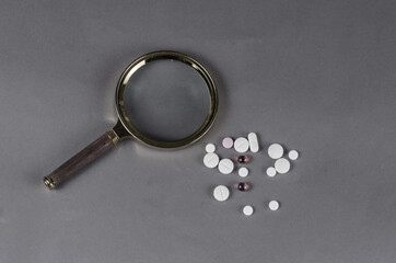 Group Medical pills and a magnifying glass on a gray background. Health and medicine concept....