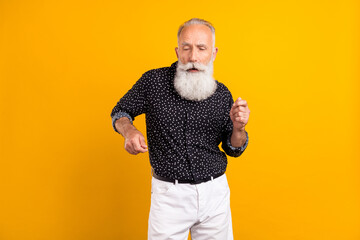 Photo of old charming cool grandfather dance enjoy wear black dotted shirt isolated on yellow color...