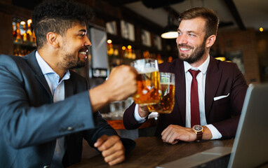 Meeting with the best friends. Happy young business men talking and drinking beer in a pub