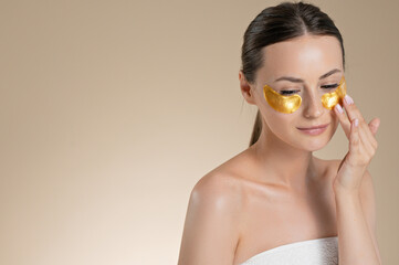 Pretty caucasian woman using collagen pads under eyes