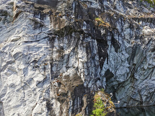 A steep slope of a flooded Marble Canyon with a gull's nest in the Ruskeala Mountain Park on a sunny summer day.