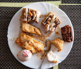 Leftovers in a plate on the table with sweets cakes, close-up