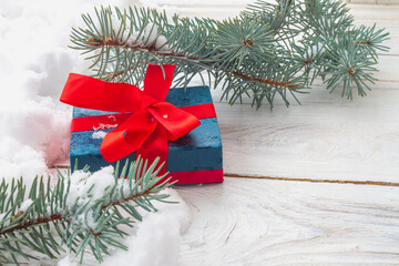 A Christmas gift in a box on a white background with snow and branches of a Christmas tree. Copy Space