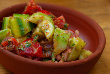Traditional Georgian vegetable salad of cucumbers and tomatoes with sauce on a national plate