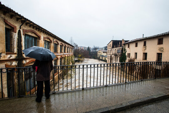Rear view of man standing on a bridge looking at flood water, Olot, La Garrotxa, Girona, Spain