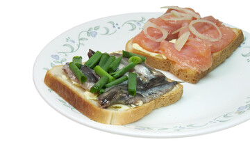 sandwich pair with slices of salted salmon and small silvery sprats, on white toast bread with butter, seasoned with chopped shallots. closeup. isolated on white background