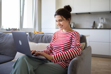 Smiling  girl freelancer using laptop studying online working from home office. Happy millennial...