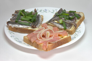 sandwiches with slices of salted salmon and solted sprats on butter, seasoned with chopped shallots