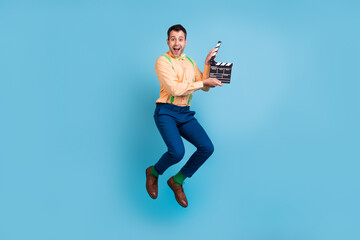 Photo of excited director guy jump shot movie hold clapper wear suspenders shirt isolated blue color background