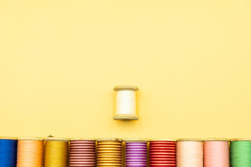 row of thread spools against yellow cream background