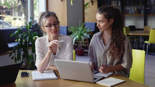 Two female students discussing new project in library