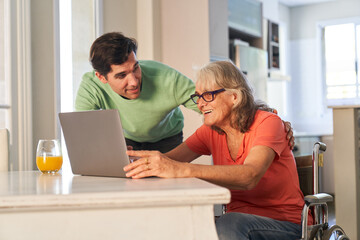 Sohn hilft seiner Senior Mutter am Laptop Computer