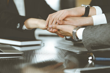 Unknown business people group joining hands in modern office. Businessmen and women making circle with their hands as a team, close-up