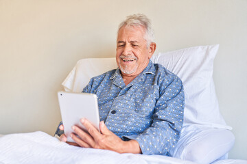 Kranker Senior mit Tablet Computer freut sich beim Videochat