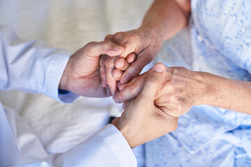 Altenpfleger oder Arzt hält die Hände einer Seniorin