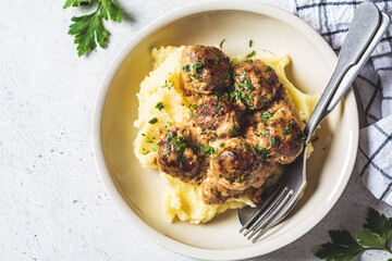 Swedish meatballs in creamy sauce with mashed potatoes in white plate, gray background. Scandinavian food concept.