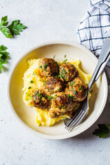 Swedish meatballs in creamy sauce with mashed potatoes in white plate, gray background. Scandinavian food concept.
