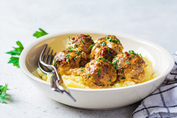 Swedish meatballs in creamy sauce with mashed potatoes in white plate, gray background. Scandinavian food concept.