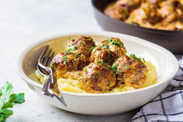 Swedish meatballs in creamy sauce with mashed potatoes in white plate, gray background. Scandinavian food concept. - obrazy, fototapety, plakaty