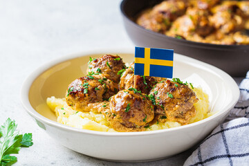 Swedish meatballs in creamy sauce with mashed potatoes in white plate, gray background....