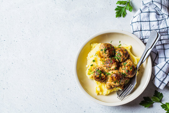 Swedish meatballs in creamy sauce with mashed potatoes in white plate, gray background. Scandinavian food concept.