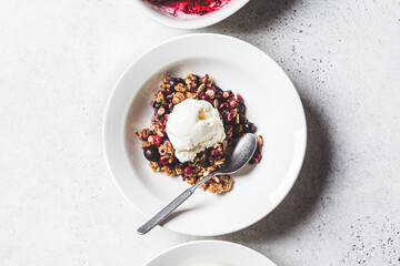 Berry crumble pie with scoop of ice cream, gray background.