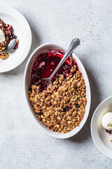 Berry crumble pie with scoop of ice cream, gray background.