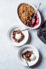Berry crumble pie with scoop of ice cream, gray background.