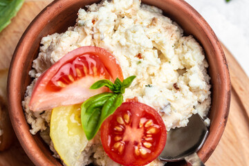 Bowl with homemade cottage cheese, cherry tomatoes and basil on a wooden board. Healthy food trend