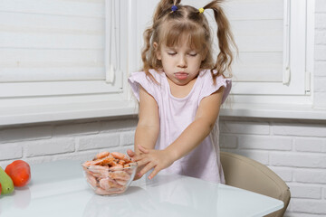 Caucasian child girl refuses to eat shrimp. Refusing to eat