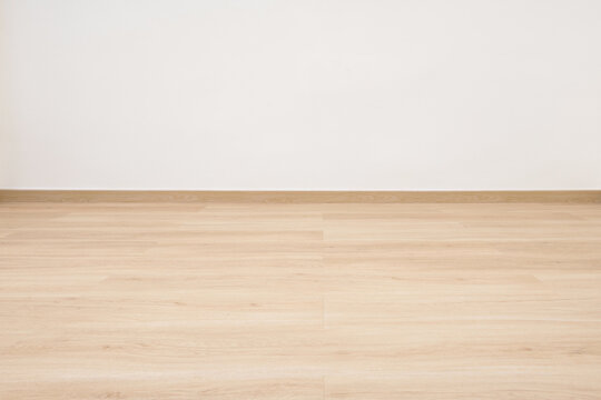 Empty wooden floor with white concrete wall.