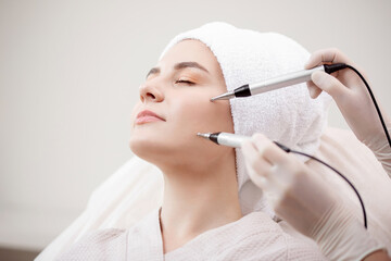 Young woman having micro current galvanic facial treatment with electrodes for lifting face....