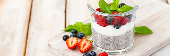Vegan low calories chia seed pudding with fresh organic berries, plant milk, mint. Concept of dieting, detox, tasty simple super food, healthy sweet desserts. Banner. Wooden background