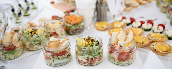 Banner decorated wedding catering banquet table with different food appetizers and snacks