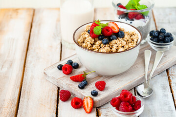 Bowl with vegan granola with fresh ripe organic berries, plant milk, mint. Concept of dieting, detox, tasty simple super food, healthy low calories breakfast. Wooden background, close up