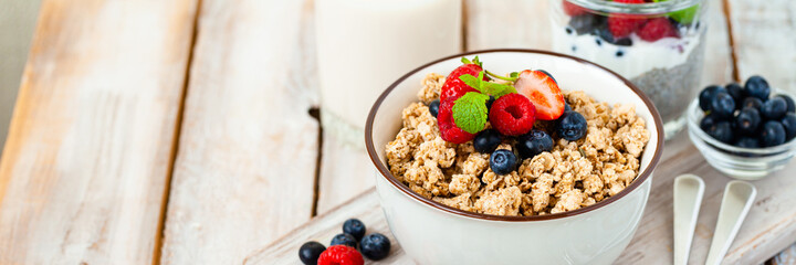 Bowl with vegan granola with fresh ripe organic berries, plant milk, mint. Concept of dieting, detox, tasty simple super food, healthy low calories breakfast. Wooden background, close up. Banner