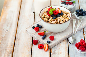 Bowl with vegan granola with fresh ripe organic berries, plant milk, mint. Concept of dieting, detox, tasty simple super food, healthy low calories breakfast. Wooden background, close up
